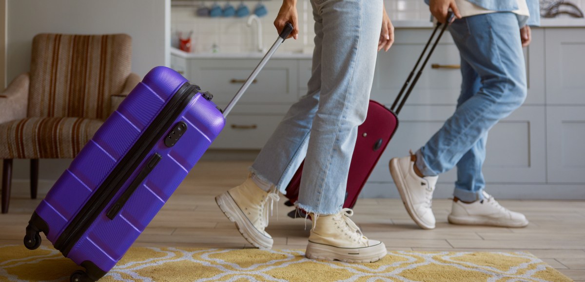 Pareja con maletas saliendo de casa para irse de vacaciones